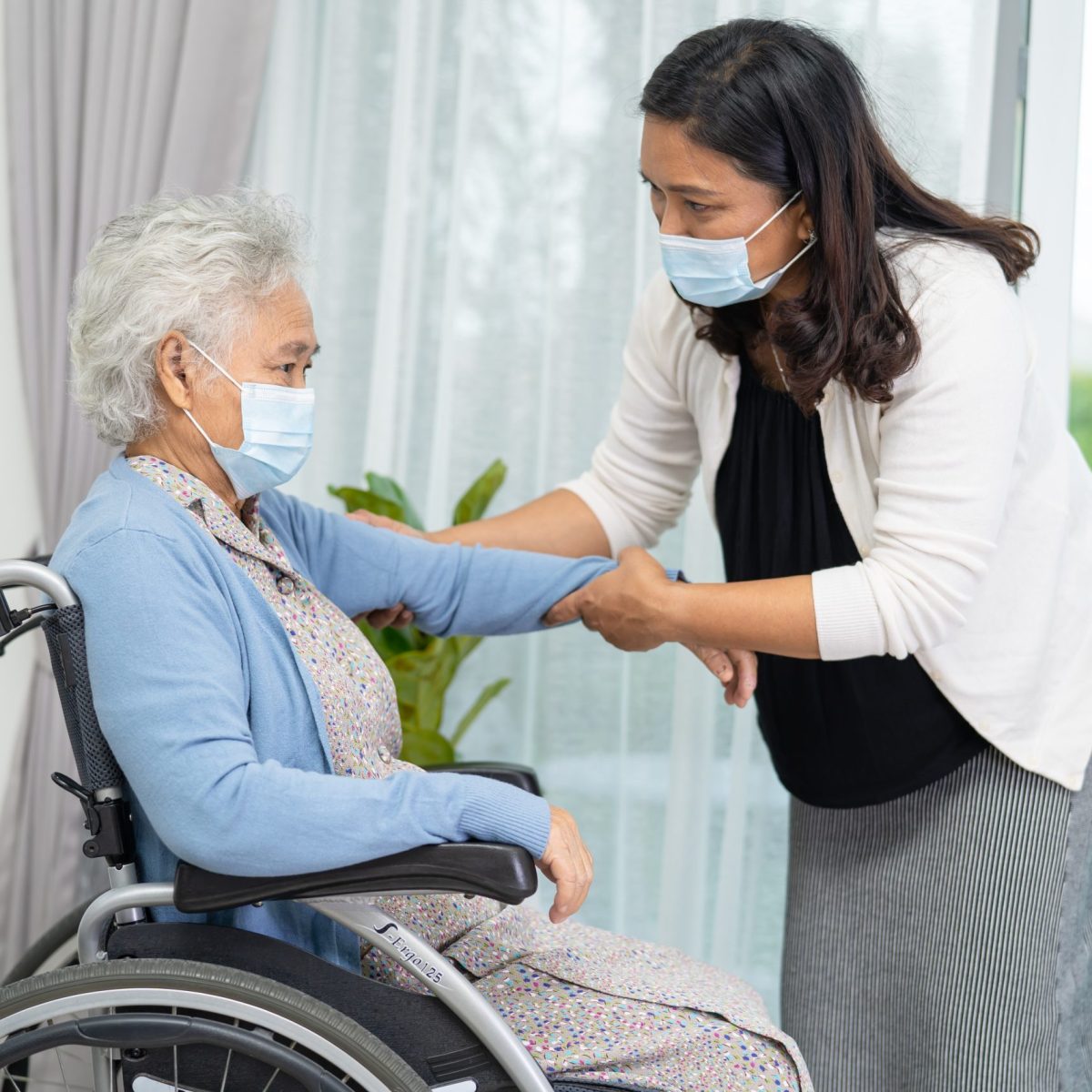 Help Asian senior or elderly old lady woman sitting on wheelchair and wearing a face mask for protect safety infection Covid-19 Coronavirus.