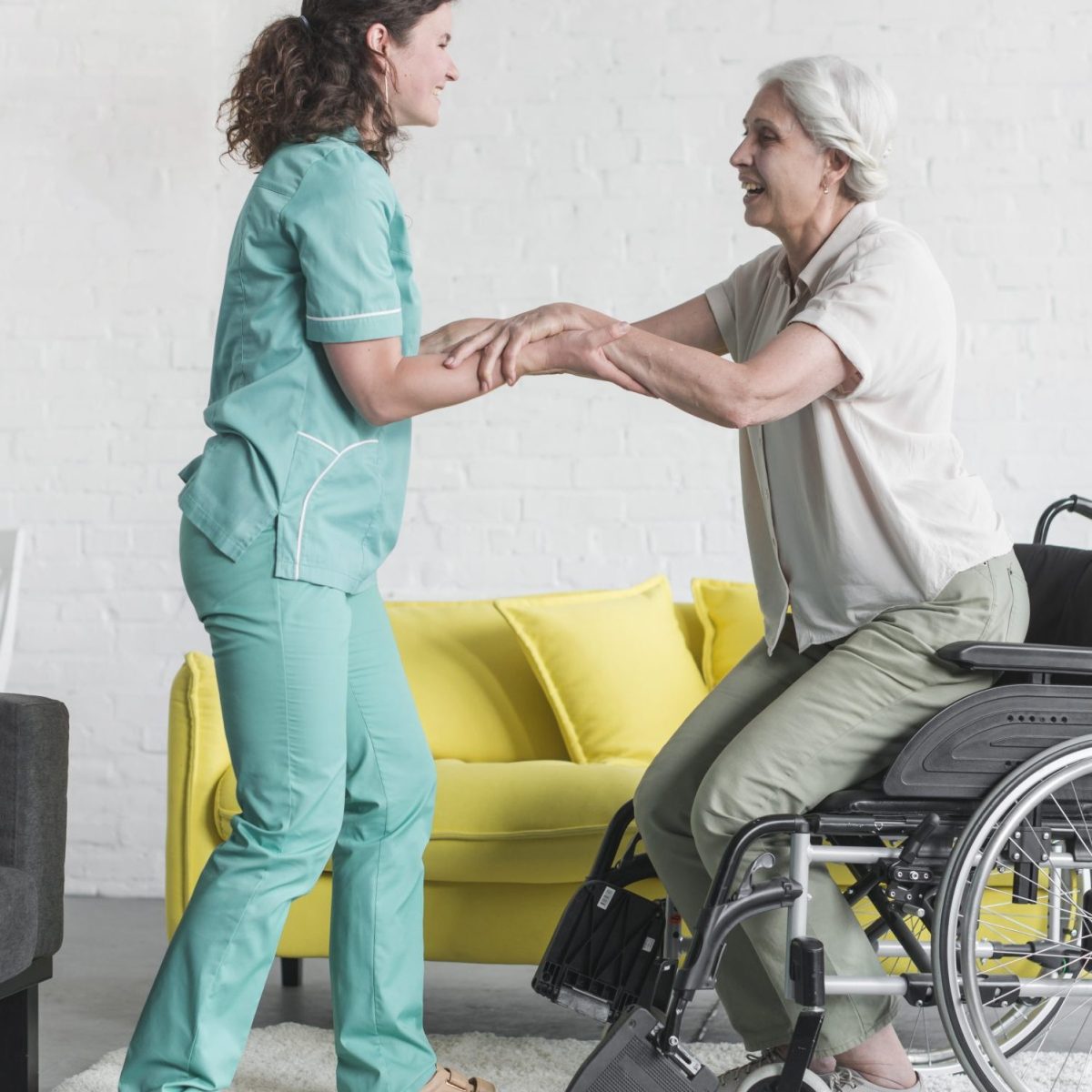 nurse-holding-disabled-senior-woman-s-hand-sitting-wheel-chair